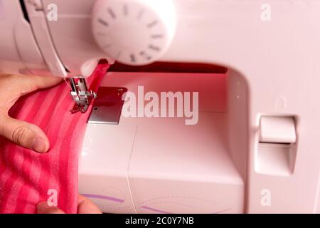 Close up photo of white sewing machine. Detail of the needle, plate, foot and transporter of an electric sewing machine. Hand using the machine. Conce Stock Photo