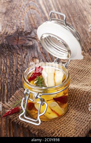 Marinated cheese in glass jar. Stock Photo