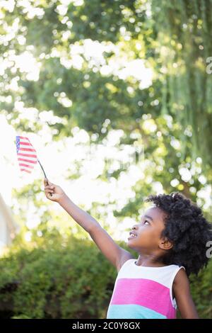 A little girl is holding an american flag in the air Stock Photo