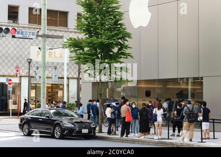 People waiting outside the Apple store in Ginza after state of emergency lifted. They are wearing face masks & practicing social distancing. Stock Photo