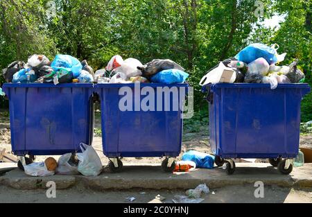 Overflowing garbage bins with household waste in the city. Stock Photo