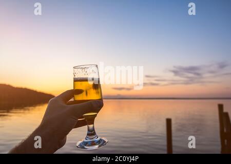 Having a fresh cold beer at the seashore during a beautiful colorful sunset Stock Photo
