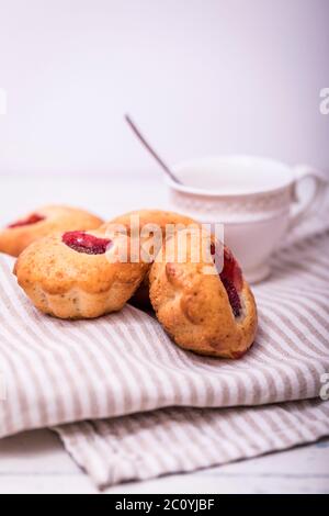 Tasty muffin cakes. Homemade buttercream cupcakes with strawberries on white wooden table. Stock Photo