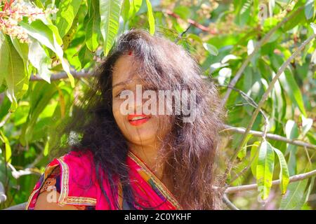 Portrait head shot of a indian young beautiful girl in open bright black hairs and polished red lips , concepts for women health care Stock Photo