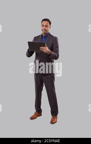 Businessman Using Tablet Isolated. Indian Business man Standing Full Length with Tablet in Hands Stock Photo