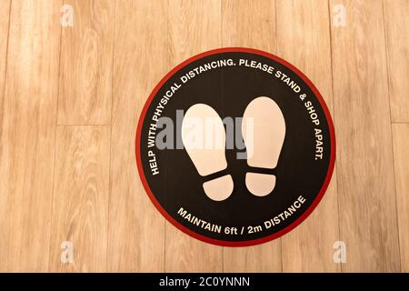 Social distancing in stores, malls or shops during pandemic or after virus. Protection customers. Sticker sign on floor. Stock Photo