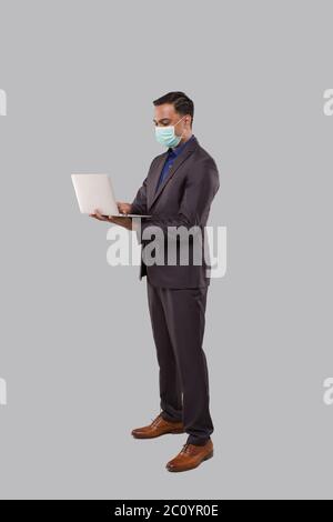 Businessman Using Laptop Green Screen Isolated Wearing Medical Mask. Indian Business man with Laptop in Hands. Online Business Concept Stock Photo