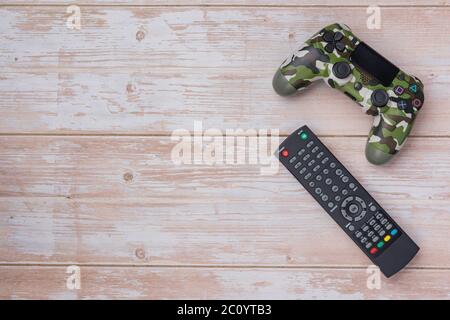 Flat lay of video game controller and TV remote control  on wooden background Stock Photo