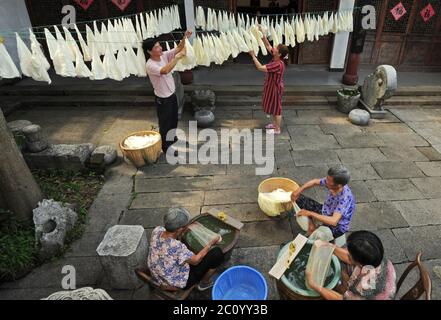 (200613) -- HUZHOU, June 13, 2020 (Xinhua) -- Wang Yishi (L Back) and his wife Ji Jinmei (R Back) dry silk materials for making silk quilt at his Jili silk museum in Huzhou City, east China's Zhejiang Province, June 12, 2020. Jili silk, produced in Jili Village of Huzhou, is famous for its high quality. It was designated as the material to make ropes for Chinese emperors since the middle of the Ming Dynasty (1368-1644). In 2011, the making technique of the silk was listed as one of the national intangible cultural heritages. It is known worldwide since 1851 when Jili silk won the first gold pr Stock Photo