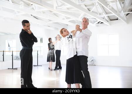 Mixed race dance teacher helping his ballroom dancing class Stock Photo