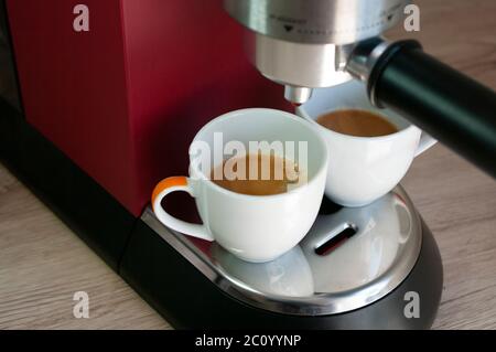 Two small cups with espresso coffee. Morning drink. Red coffee machine. Stock Photo