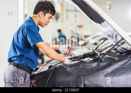 Asian mechanic Checking and repairing the car in maintainance service center which is a part of showroom, technician or engineer professional work for Stock Photo