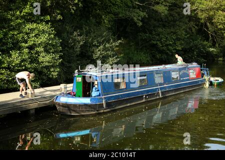Two men mooring a blue narrow boat onto a jetty on the River Medway near Hadlow, Kent Stock Photo