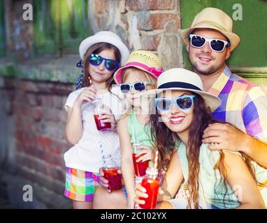 Happy young family in the street wearing hats and sunglasses Stock Photo