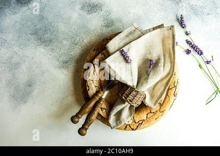 Summer time table set with vintage wooden plates and cutlery served on stone table and decorated with fresh lavender flowers Stock Photo