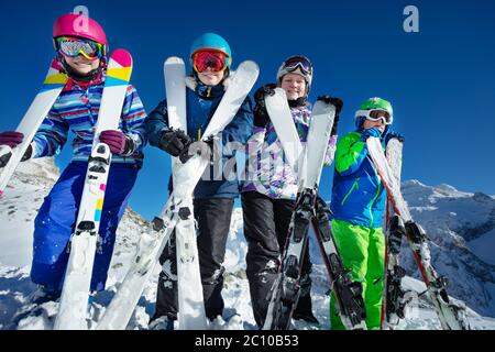 Ski vacation portrait many kids stand with sport equipment in hands lean to camera wearing color google and helmets Stock Photo