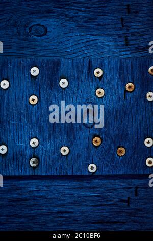 The texture of dark blue wood with old screws. Texture of old dried plywood. Classic blue background for design. Stock Photo