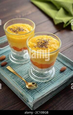Homemade chia seed pudding with mango and almond in glass on wooden background Stock Photo