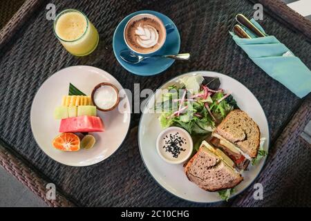 Sandwich, salad and bread basket with butter, jam and coffee on table, top view. Breakfast concept. Stock Photo