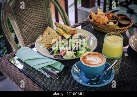 Sandwich, salad and bread basket with butter, jam and coffee on table in cafe closeup. Breakfast concept. Stock Photo