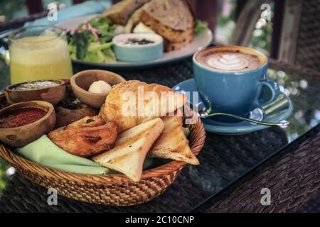 Croissant and bread basket with butter, jam and coffee on table in cafe closeup. Breakfast concept. Stock Photo