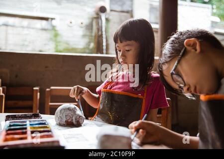 brother and sister coloring clay handicrafts with brushes and paint in the pottery workshop gallery Stock Photo