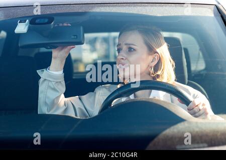 Woman drives her car for the first time, tries to avoid a car accident, is very nervous and scared, worries, clings tightly to the wheel, looking in t Stock Photo