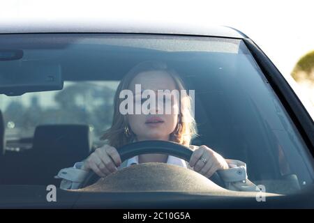 Woman drives her car for the first time, tries to avoid a car accident, is very nervous and scared, worries, clings tightly to the wheel. Stock Photo