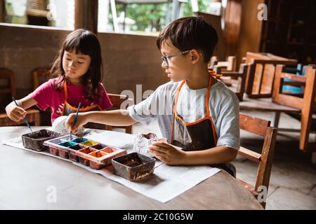 children coloring clay handicrafts with brushes and paint in the pottery workshop gallery Stock Photo