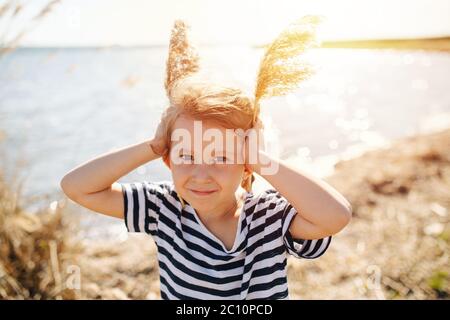 Happy lively little girl with cereal antennas by the lake at spring Stock Photo