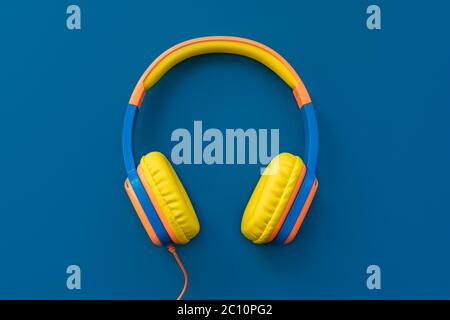 Multi-colored headphones on blue background. Minimalistic fashion music concept. Trendy color of the year concept. Top view, flat lay, copy space. Stock Photo