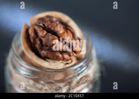 Fresh tasty walnuts in a glass jar close-up with beautiful bokeh in the background. Stock Photo