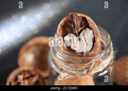 Fresh tasty walnuts in a glass jar close-up with beautiful bokeh in the background. Stock Photo