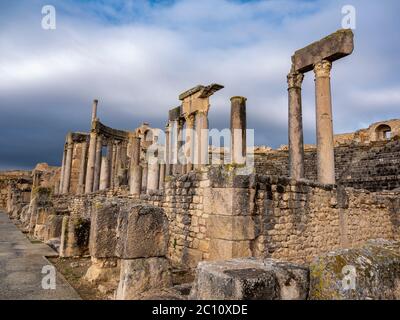 The ancient Roman archeological site of Dougga (Thugga), Tunisia, with dramatic columns at the entrance to the well preserved amphitheatre Stock Photo