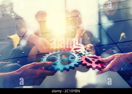 Working group of businessmen find the agreement by holding a piece of gear in hand. concept of teamwork and business partnership. double exposure Stock Photo