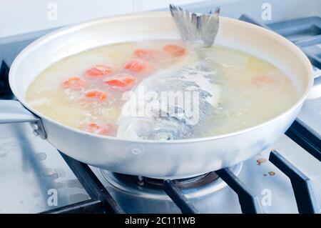 Fish bream cooked in crazy water, typical recipe of southern Italy with sea water, tomatoes, onions and garlic Stock Photo