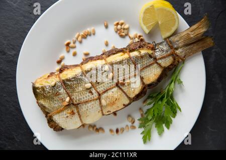 A bass, Dicentrarchus labrax, that has been de-boned and stuffed with a breadcrumb, egg, parsley, pine nut, lemon zest, lemon juice and melted butter Stock Photo