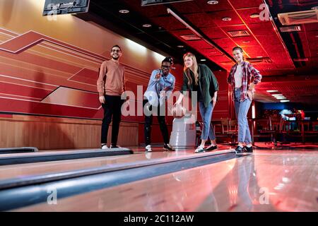 Pretty girl in casualwear going to throw ball on track while African young man pointing forwards and giving her advice durirng game Stock Photo