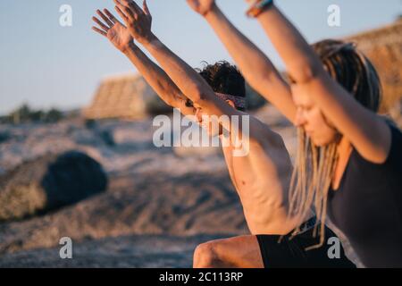 fitness, sport, and lifestyle concept - couple making yoga exercises on beach Stock Photo