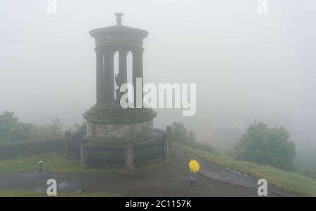 Edinburgh, Scotland, UK. 13 June 2020. A thick fog ,or haar as it is called locally, covers the city and obscures the famous tourist viewpoint from Calton Hill. Normally the viewpoint is busy with tourists , however, with the fog and Covid-19 lockdown continuing, only a few members of the public ventured up the hill today. The Dugald Stewart Monument is visible but not the famous Edinburgh skyline.  Iain Masterton/Alamy Live News Stock Photo