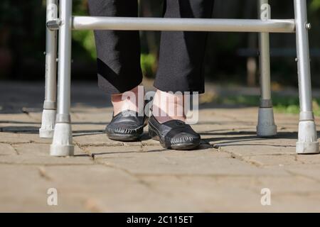 Elderly woman swollen feet using walker in backyard Stock Photo