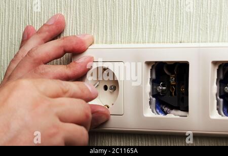 Worker man electrician is repairing damaged sockets in the apartment, installation of new  closeup Stock Photo