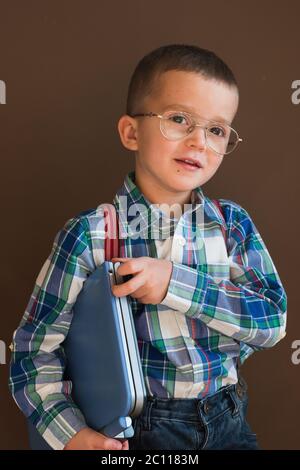 Portrait of a cute serious boy using a laptop. Child in glasses with a laptop Stock Photo