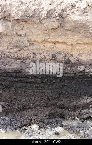 the trench depth and the earth layers, visible under peat extraction in preparation for the construction of the road. Stock Photo