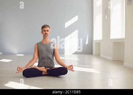 Yoga man. Bearded guy is practicing yoga in a lotus position sitting in a studio Stock Photo