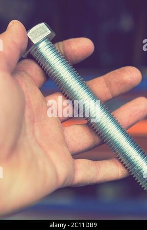 hand holds an iron bolt. repair concept. close-up. vertical photo Stock Photo