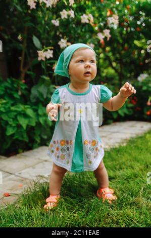 Little girl in in a turquoise kerchief making her first steps. Little girl's portrait Stock Photo