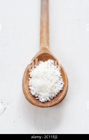wooden spoon of desiccated coconut on wooden white painted table Stock Photo