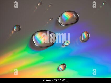 Closeup of rainbow colored reflection and water droplets on CD Stock Photo