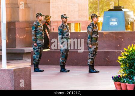 An army soldiers standing under the India Gate war memorial wearing military uniform on an evening. It is the most visited attraction by tourists. Stock Photo